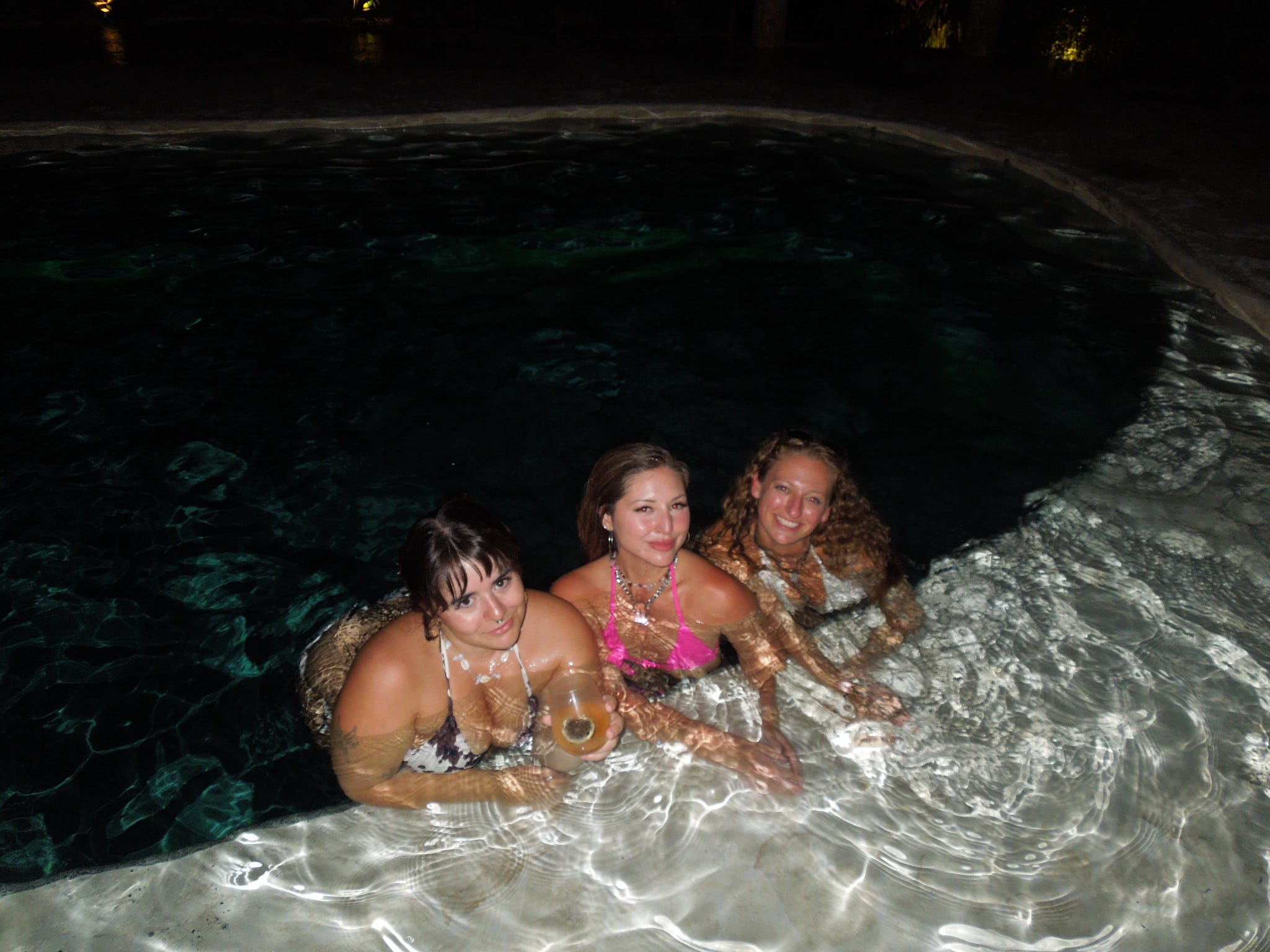 Three friends in the glowing pool late at night