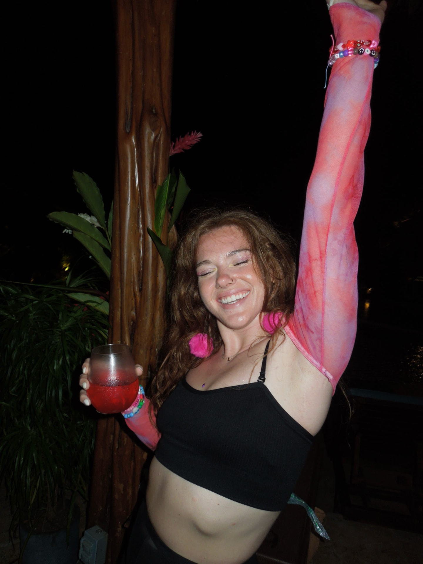 A guest dancing with her arm raised and a cocktail at the jungle bar