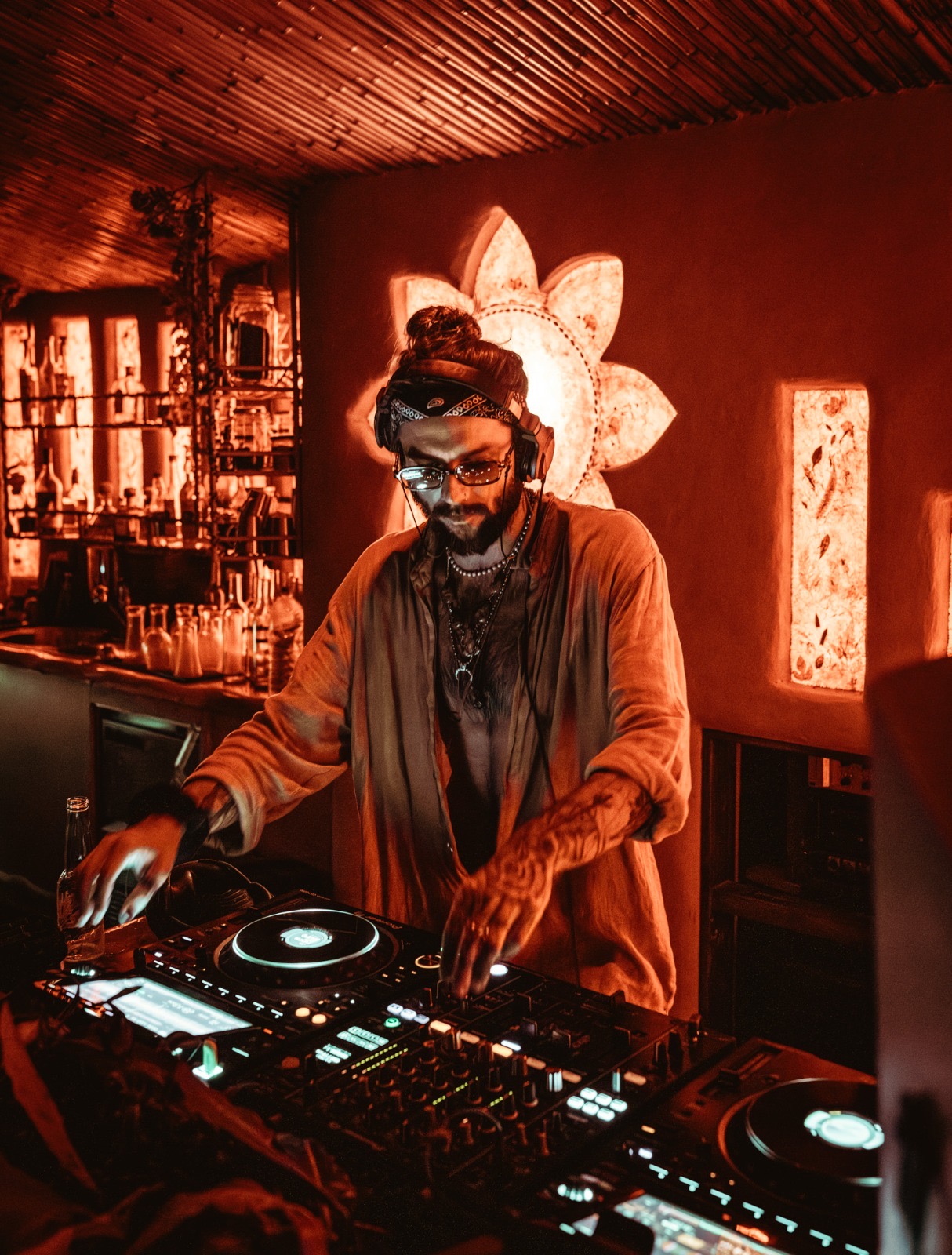 DJ on the decks at the bamboo bar washed in deep red light
