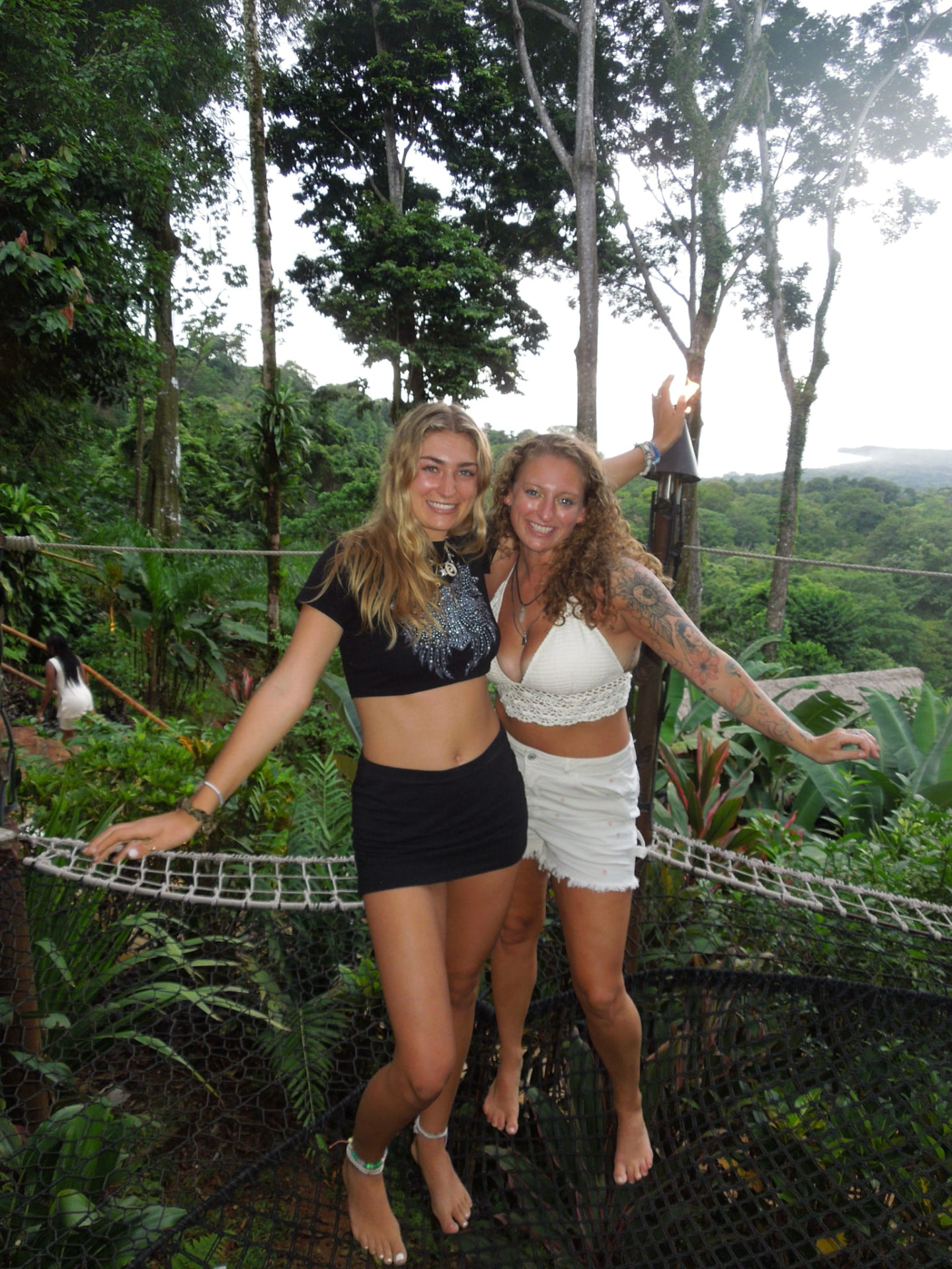 Two friends posing on the rope bridge over the jungle canopy