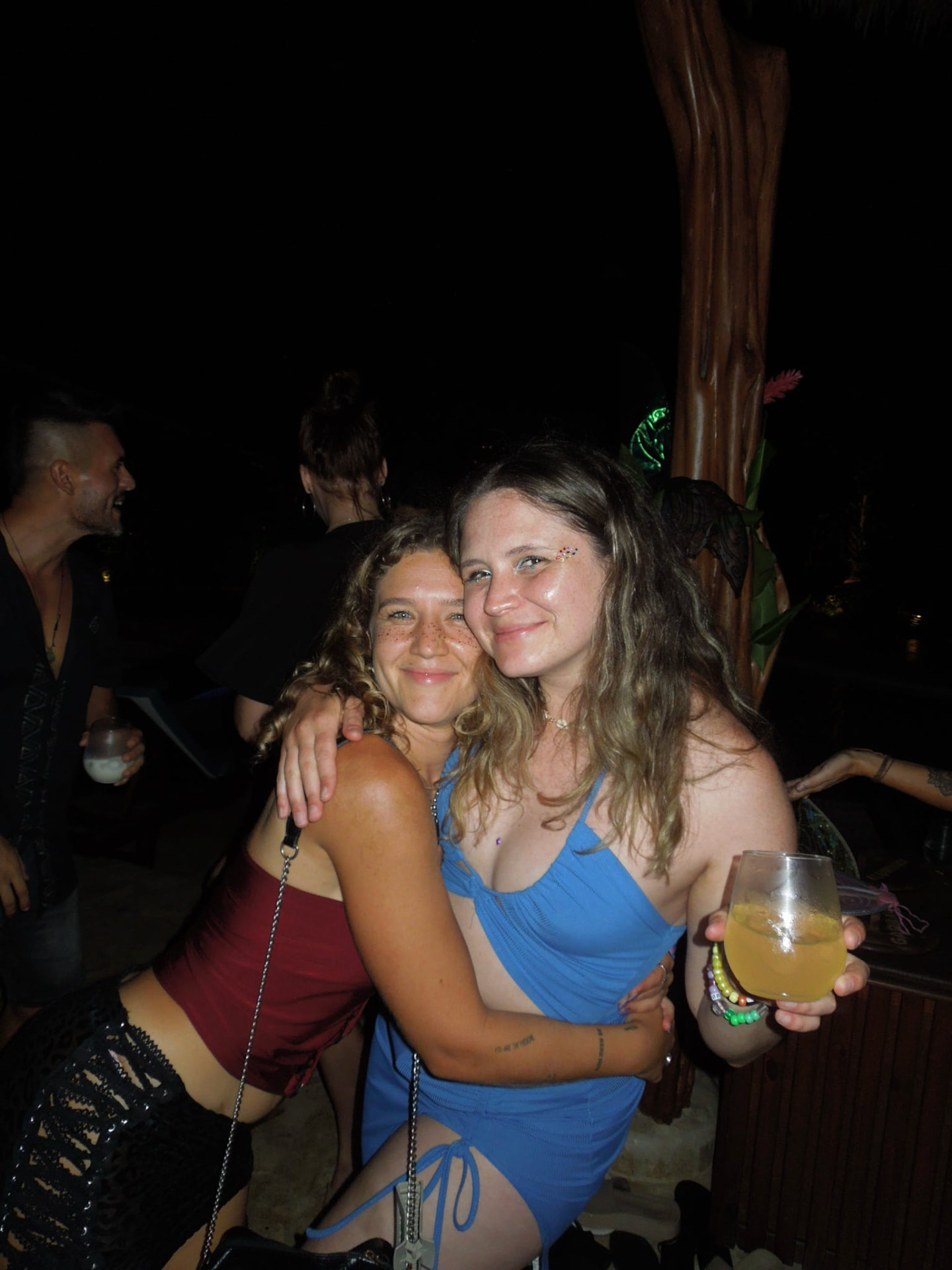 Two friends hugging with drinks at the night party