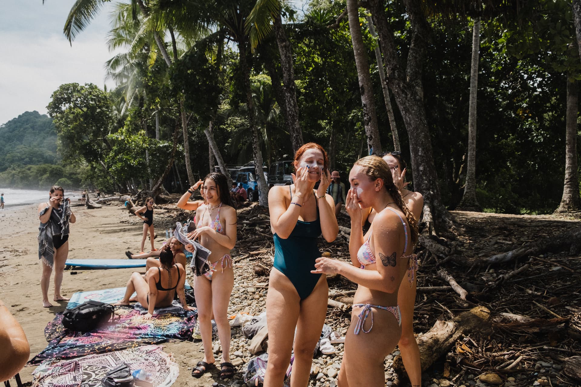 The crew putting on sunscreen on the palm-lined beach before a surf