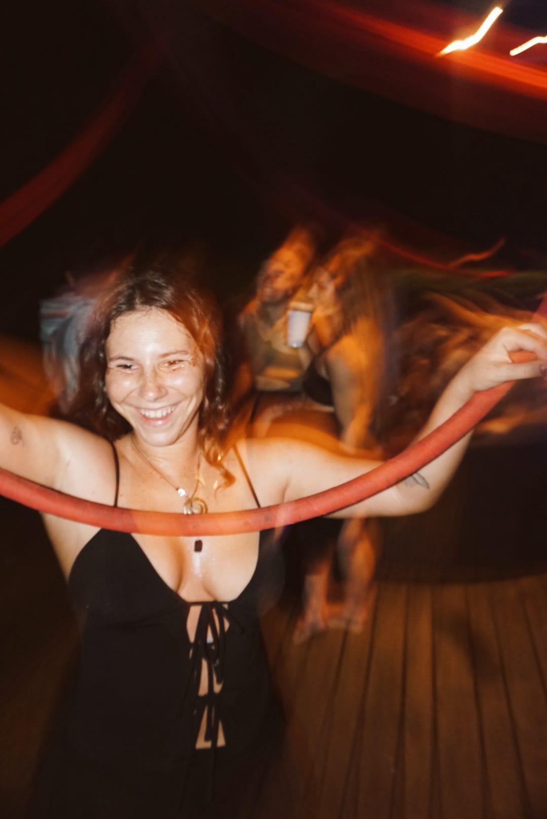 Guest laughing while dancing with a hoop on the deck at night