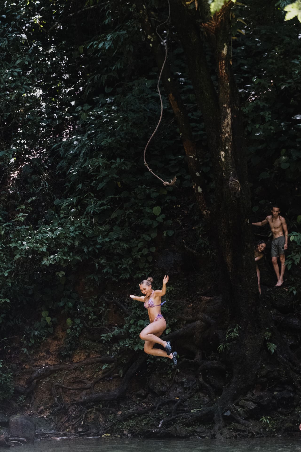Letting go of the rope swing into the jungle river