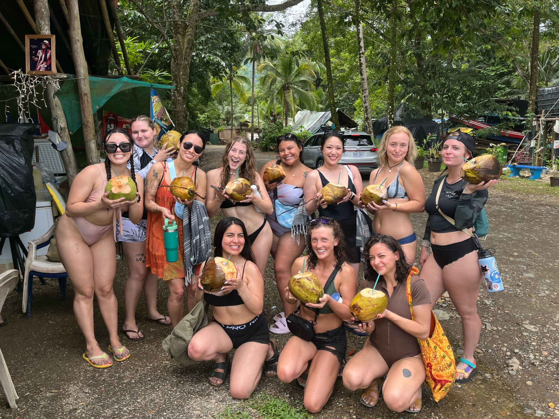 Group of retreat guests holding fresh coconuts on a jungle road