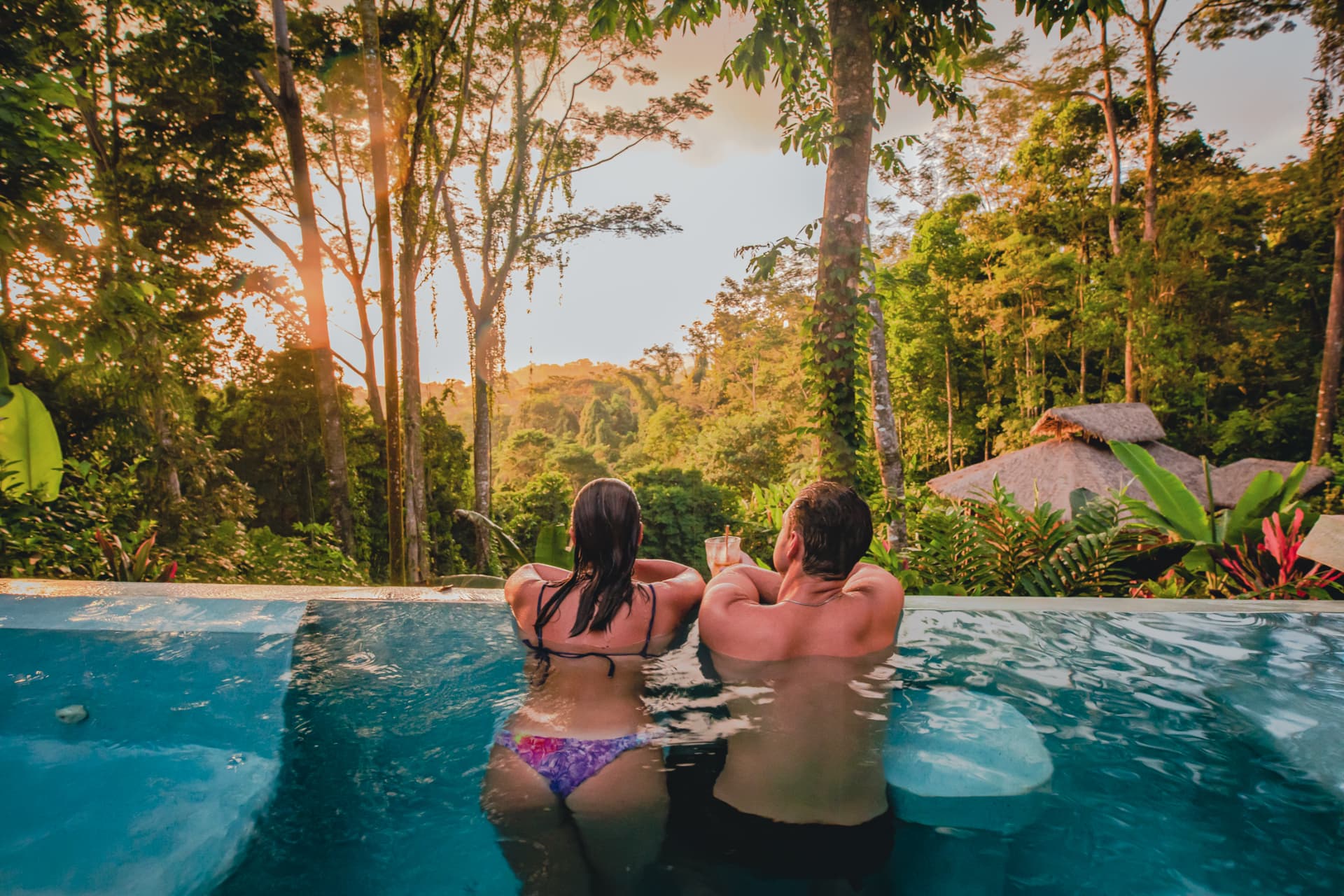 Two people in the infinity pool at Selva Armonia at golden hour