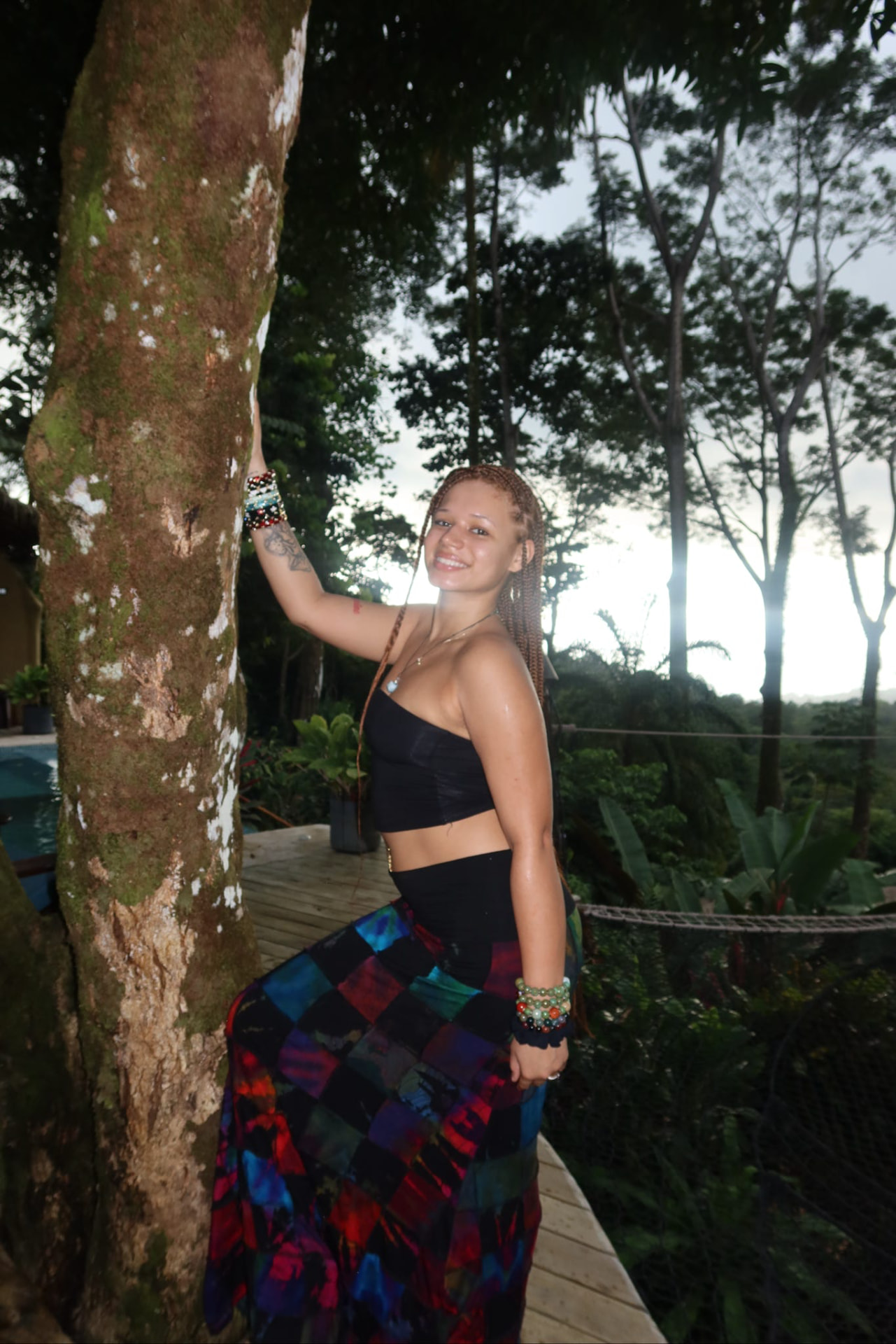 Guest posing by a mossy tree on the deck at sunset