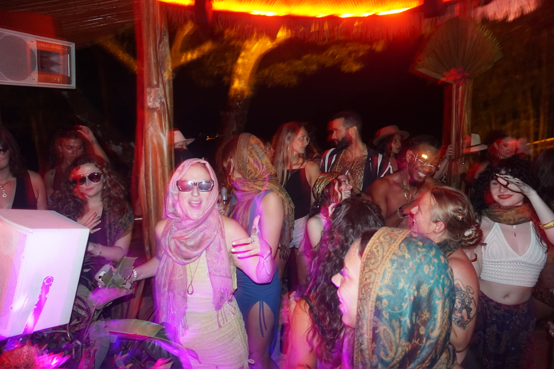 Packed dance floor under the palapa, pink and red lights everywhere