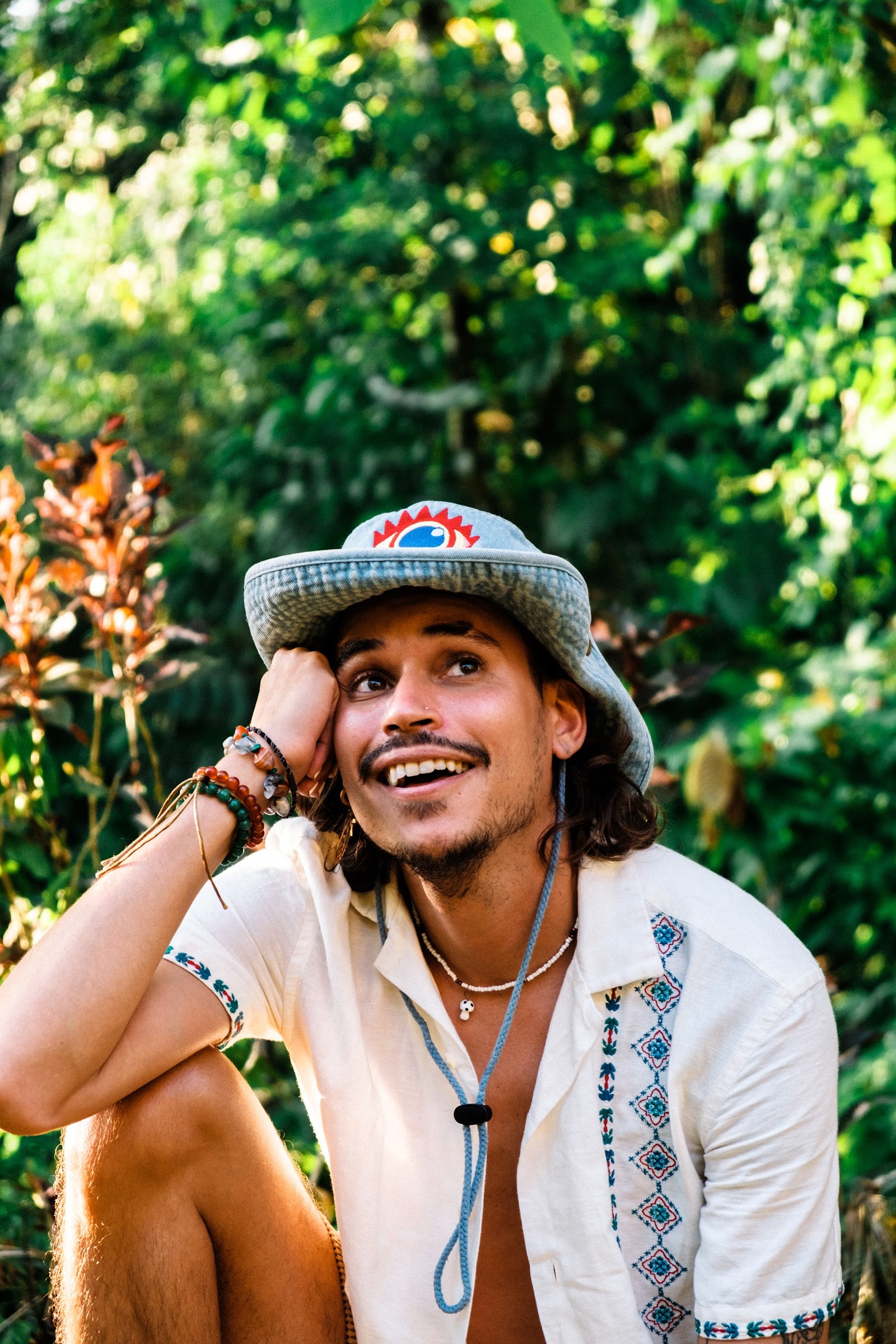 Retreat guest smiling in a straw hat surrounded by jungle leaves