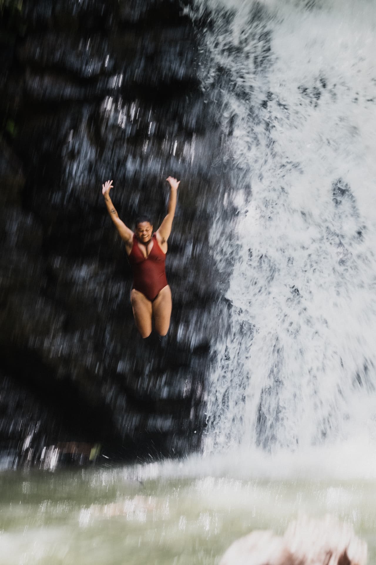 Jumping off the waterfall with arms in the air