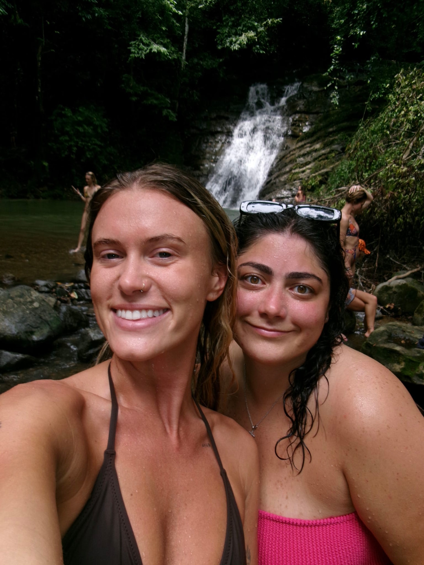 Two friends taking a selfie in front of a waterfall