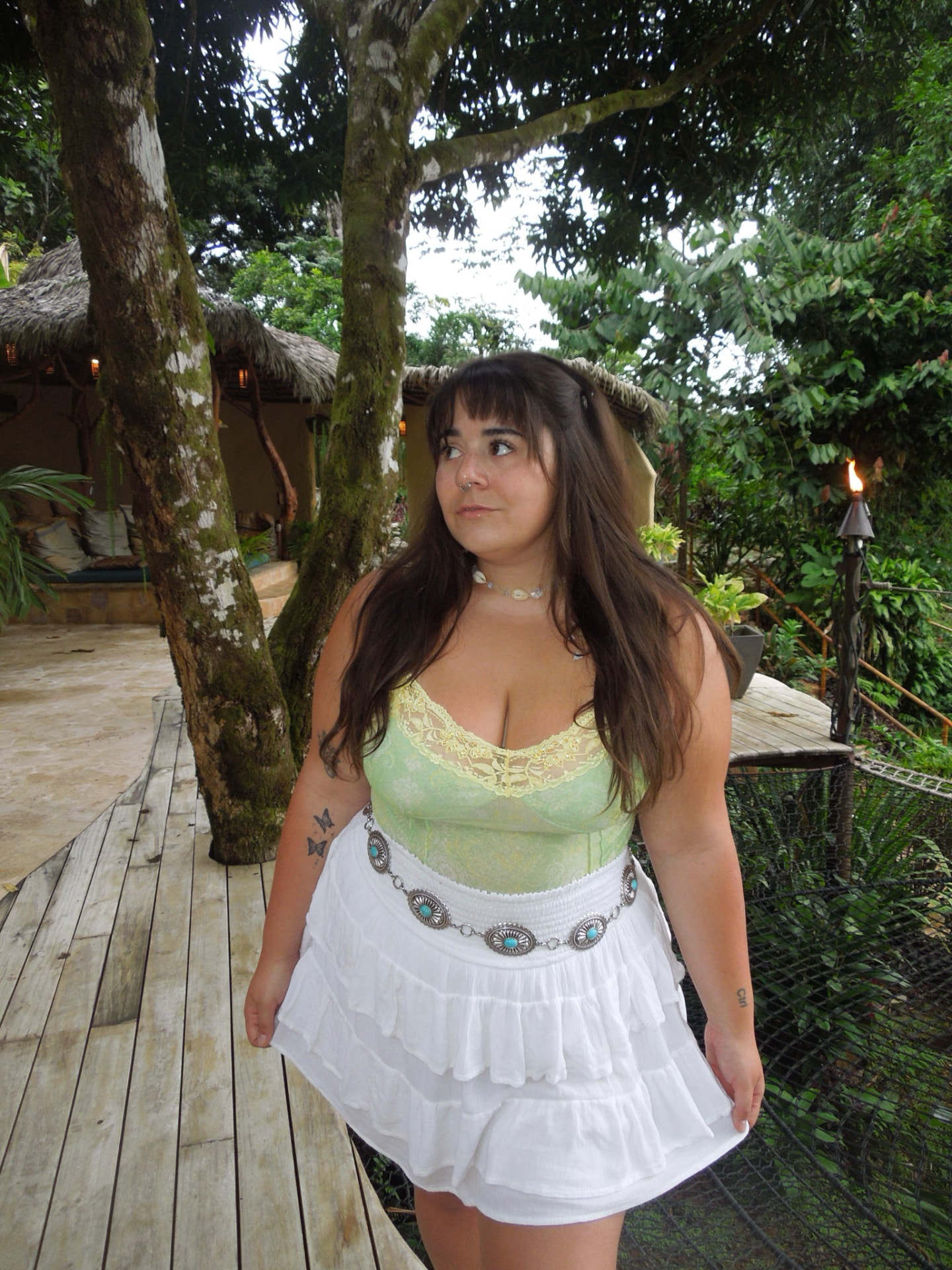A guest in a white skirt on the wooden jungle walkway at dusk