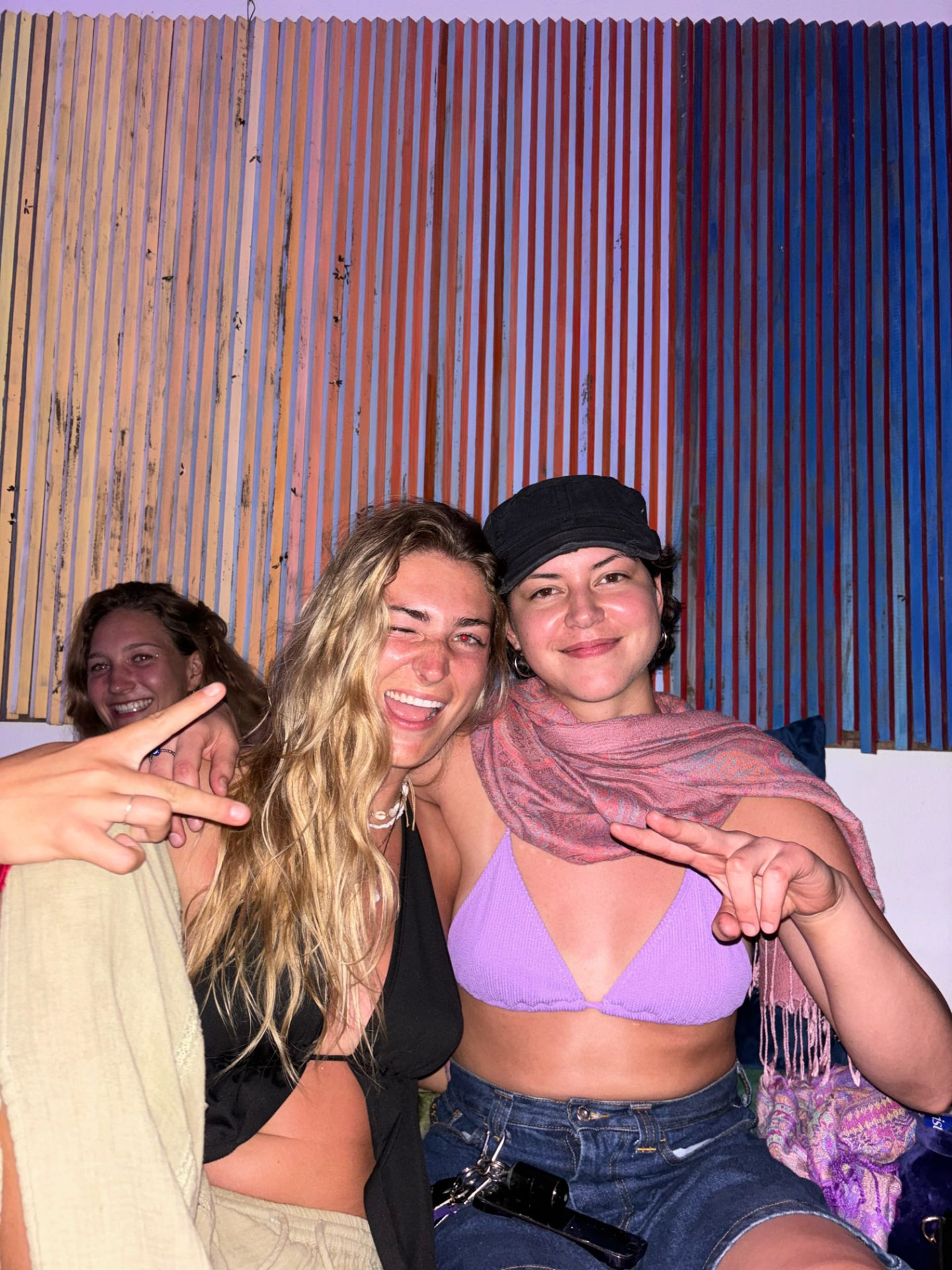 Friends throwing peace signs at the colorful jungle bar at night