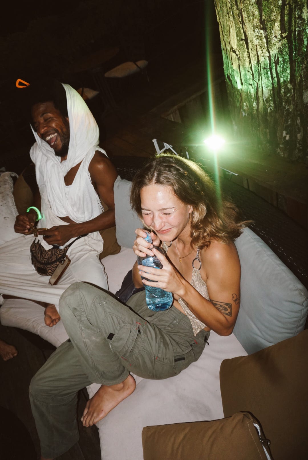 Friends laughing together on the lounge daybeds at night