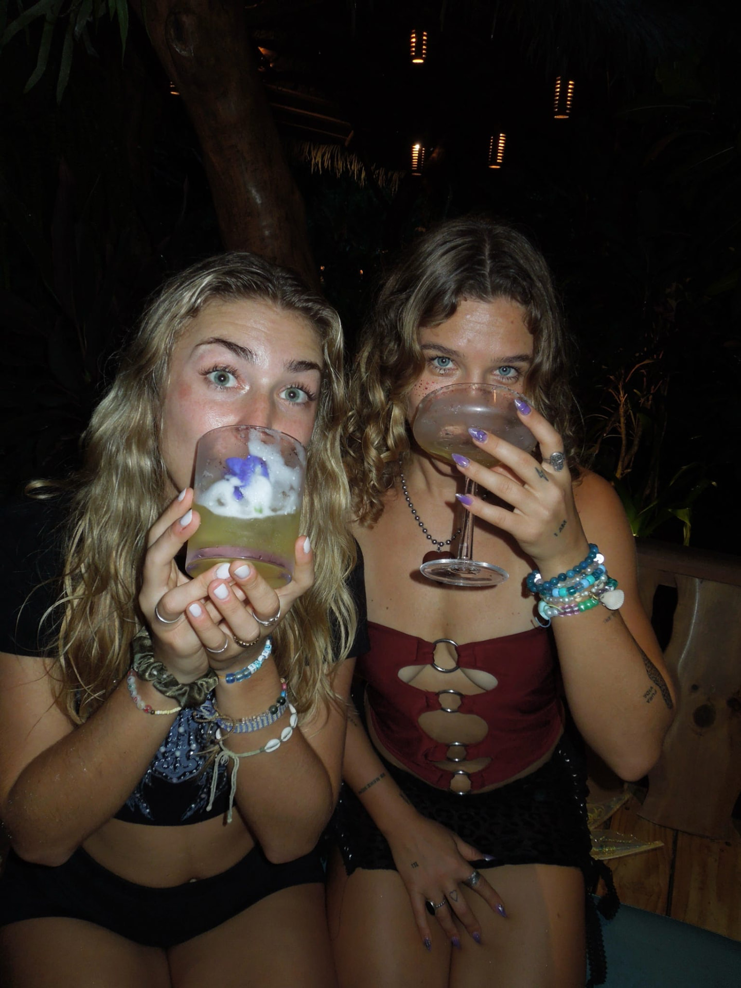 Two friends sipping cocktails together on a night out at the bar