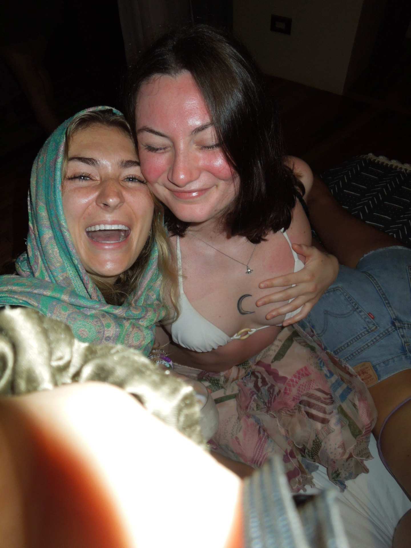 Two friends cheek to cheek laughing during a night celebration