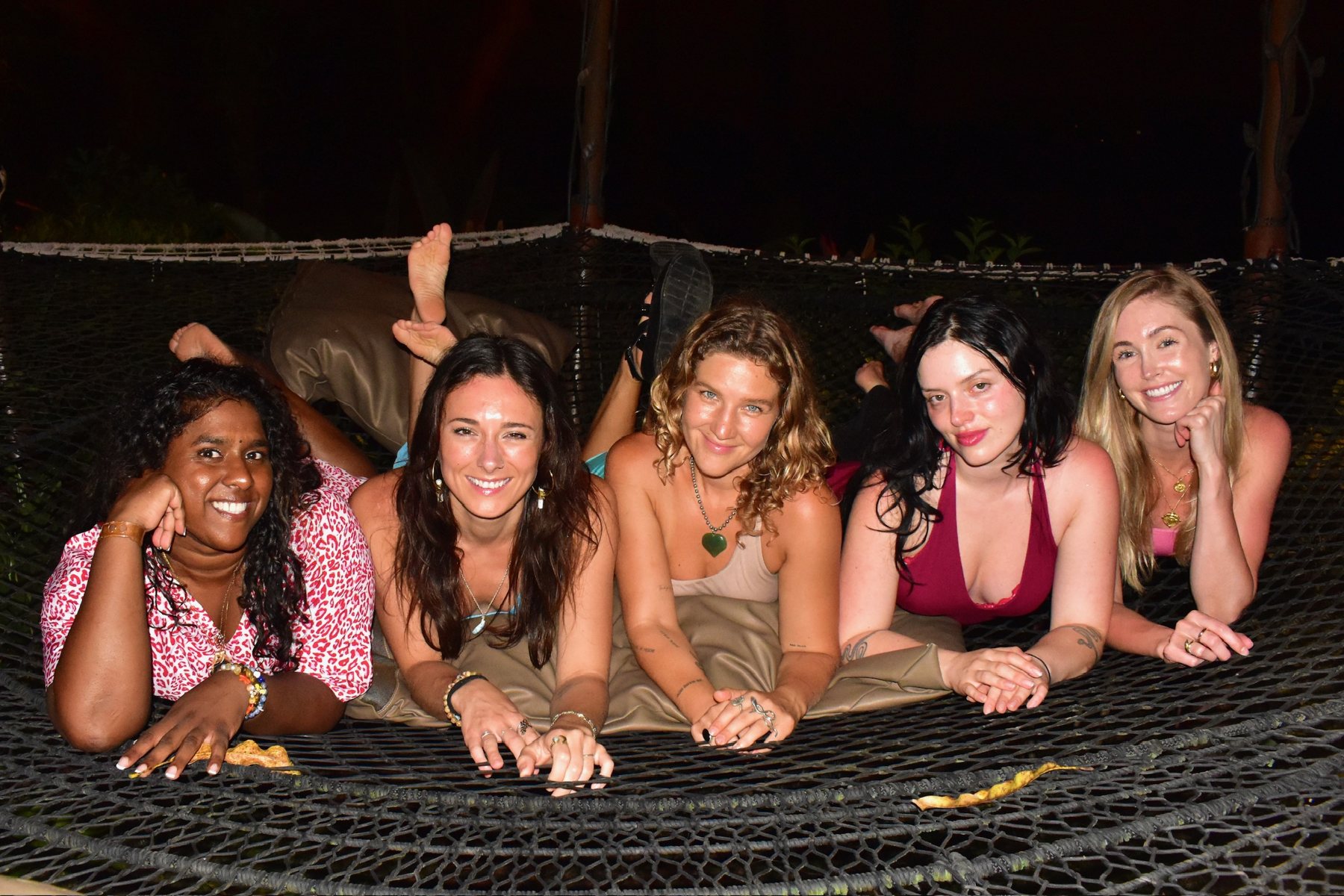 Five friends lying side by side on the hammock nets at night