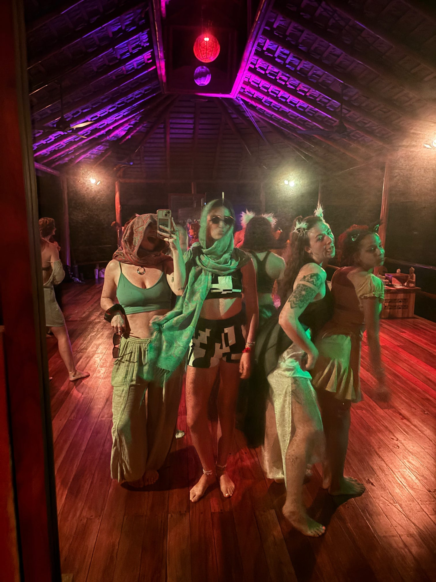Crew in scarves posing in the shala under purple and green lights