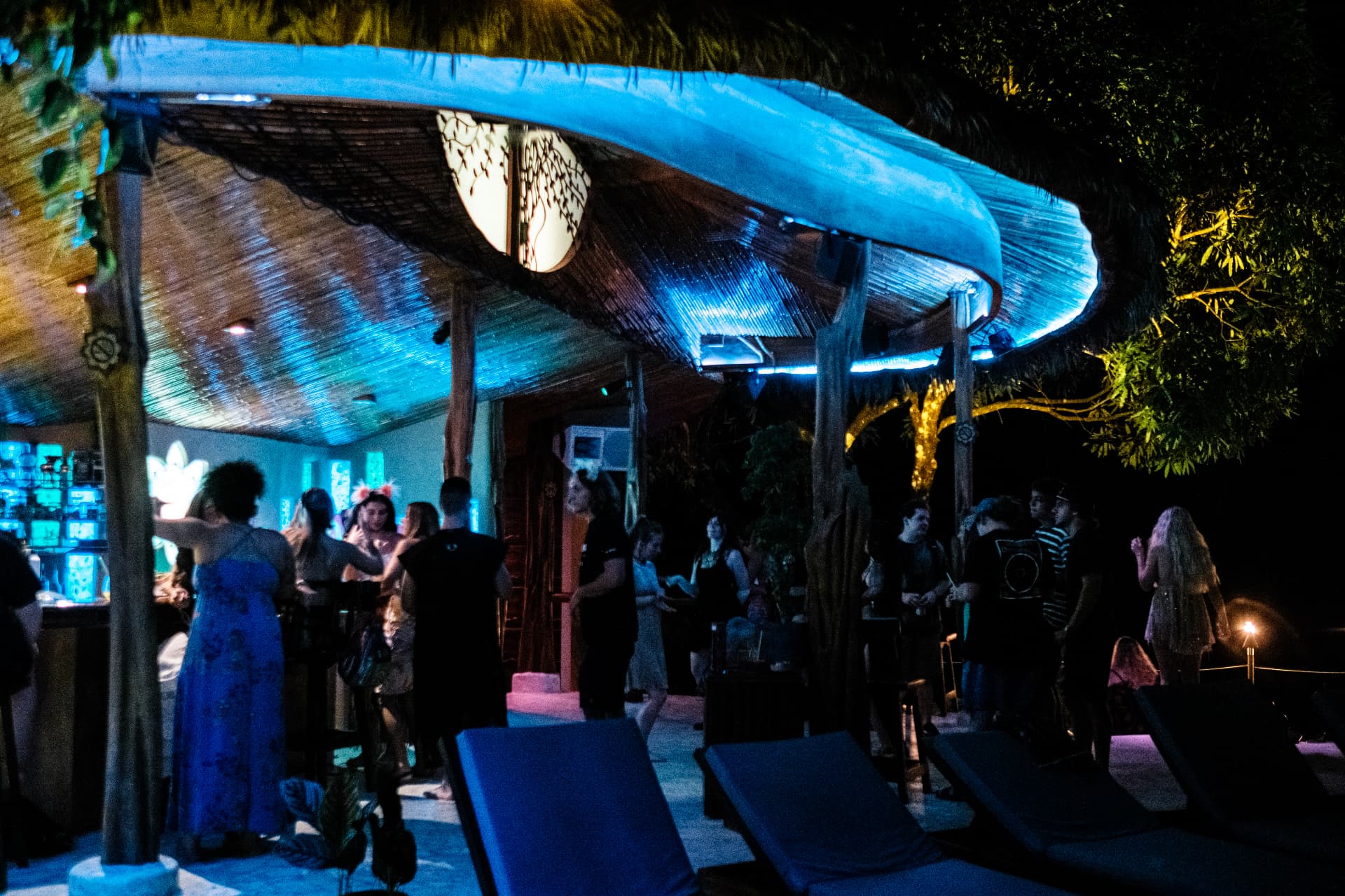 Guests gathered under the blue-lit palapa bar at night