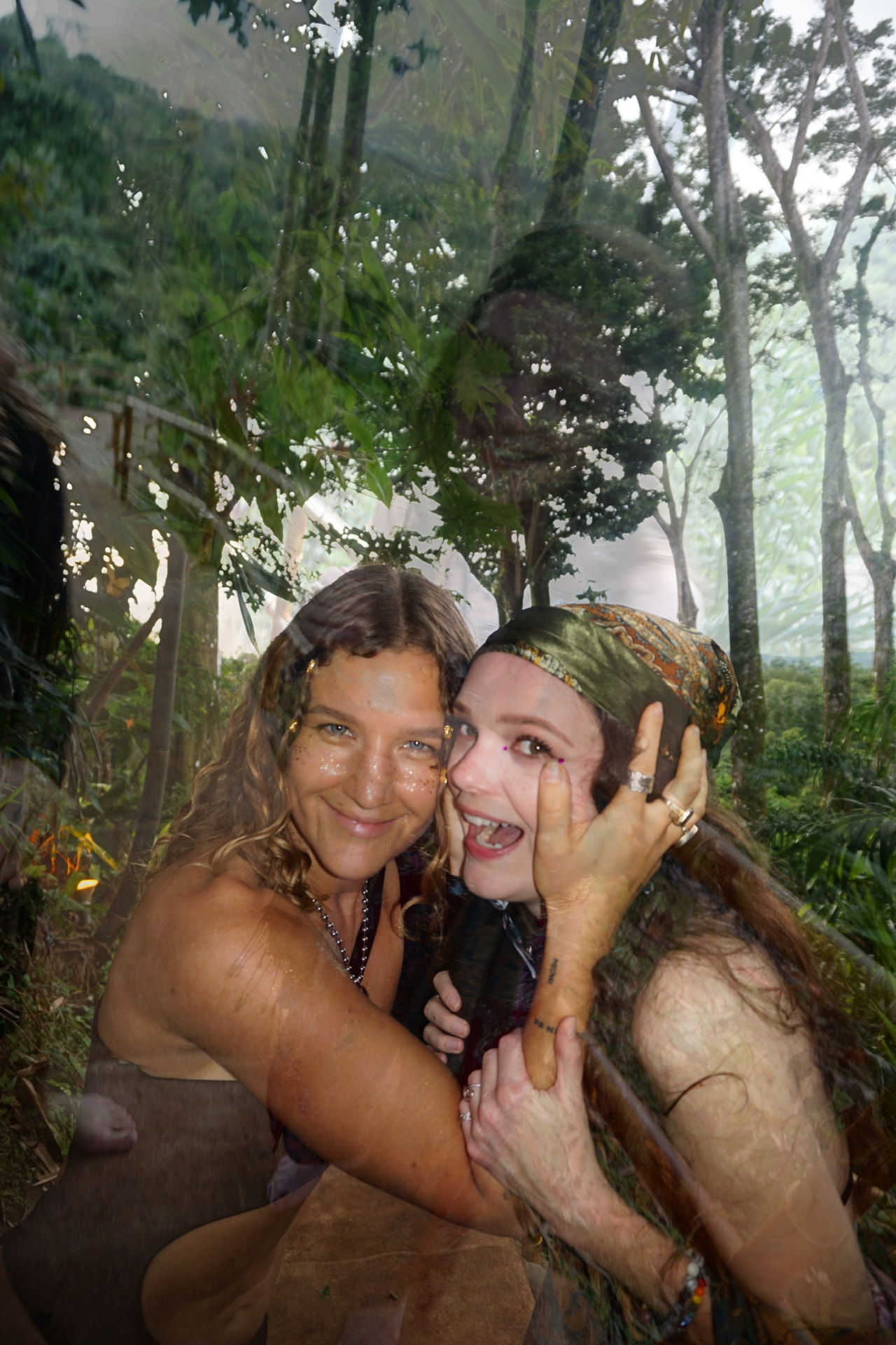 Two friends hugging in the jungle with glitter on their faces