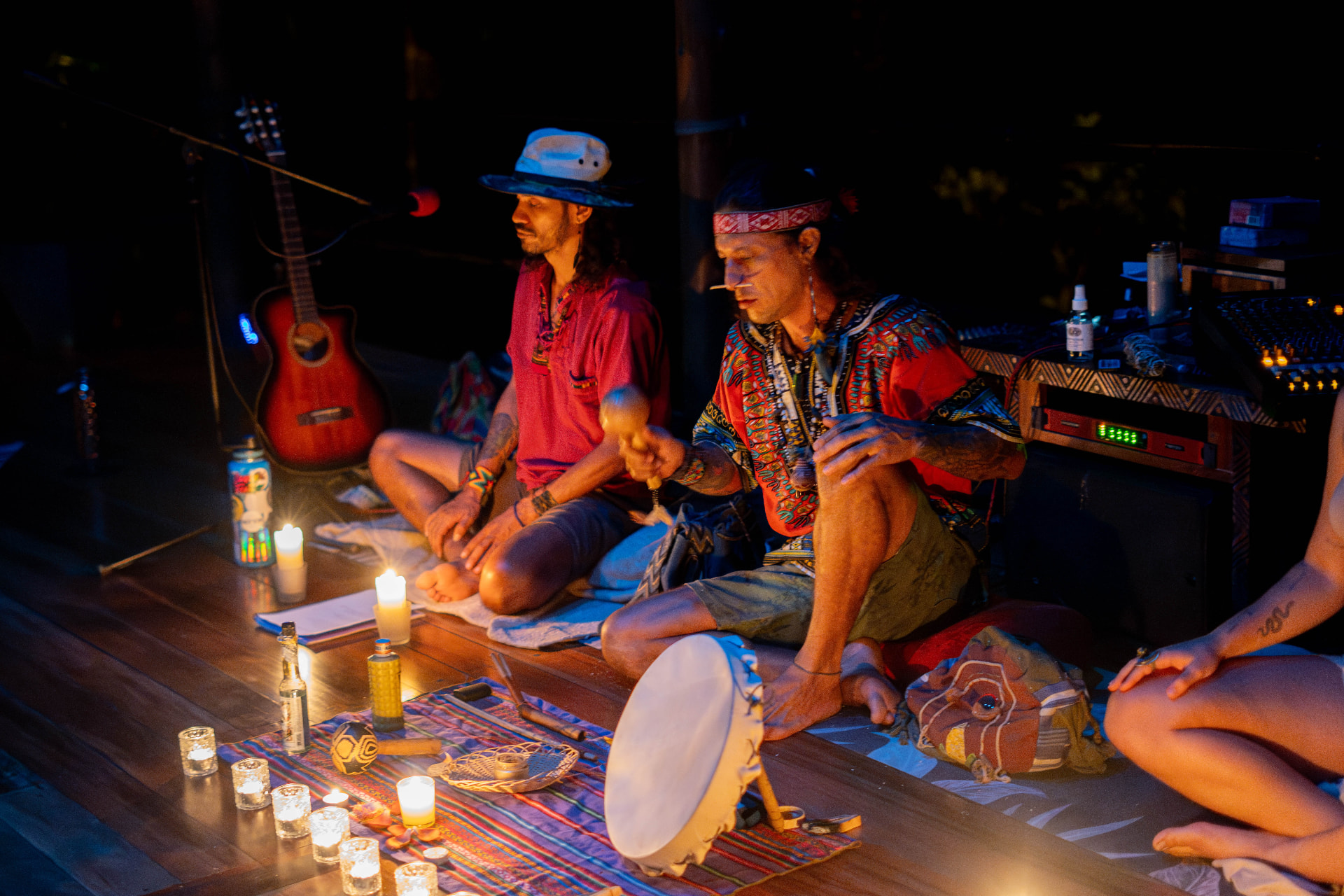 Musicians playing guitar and drum during a night ceremony in the shala