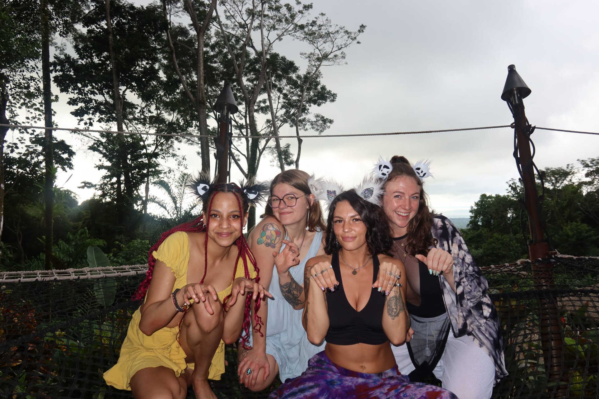 Four friends in kitty ears posing on the jungle nets at dusk