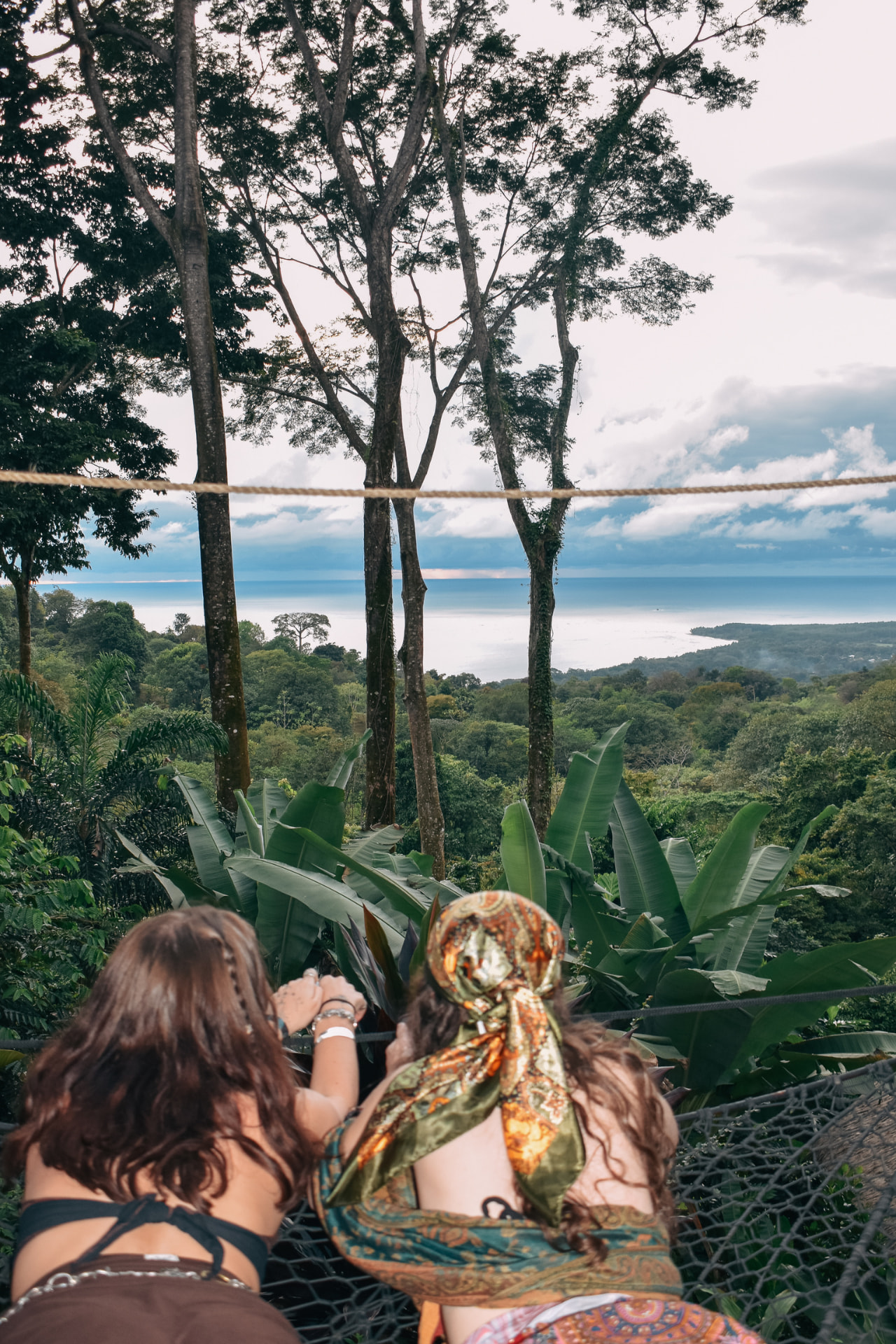 Two guests lying in the hammock nets looking out over the jungle to the ocean