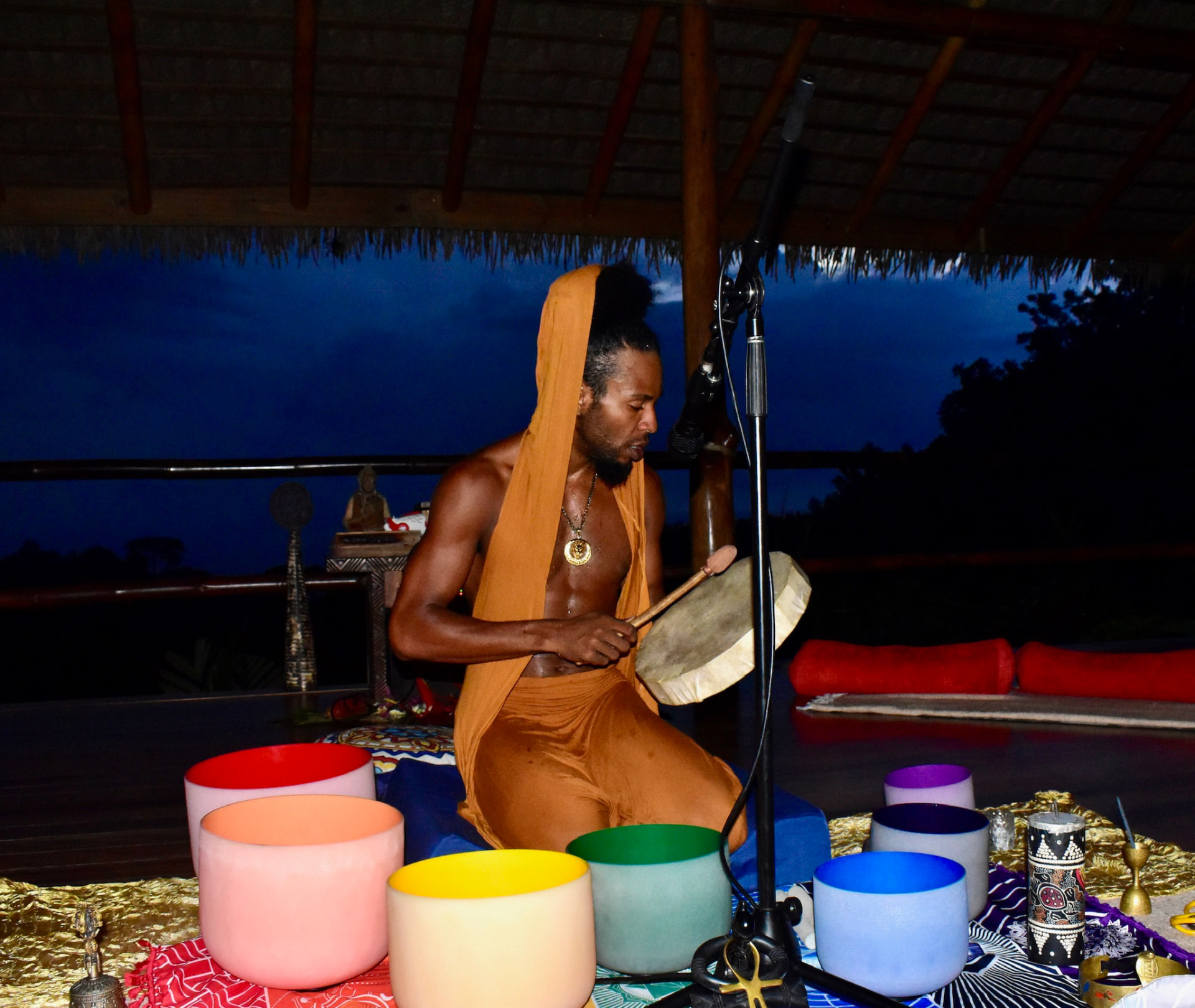 The Troy Story 3 playing a drum surrounded by colorful crystal singing bowls
