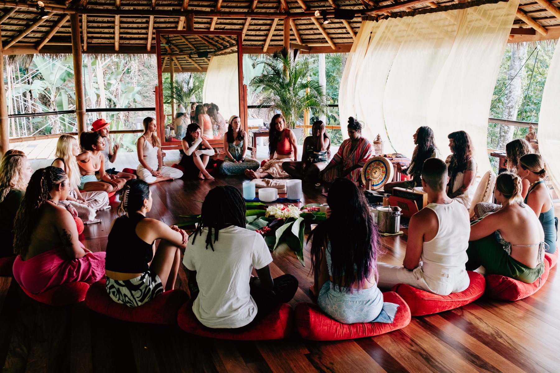 Circle gathered in the open-air yoga shala with the jungle beyond