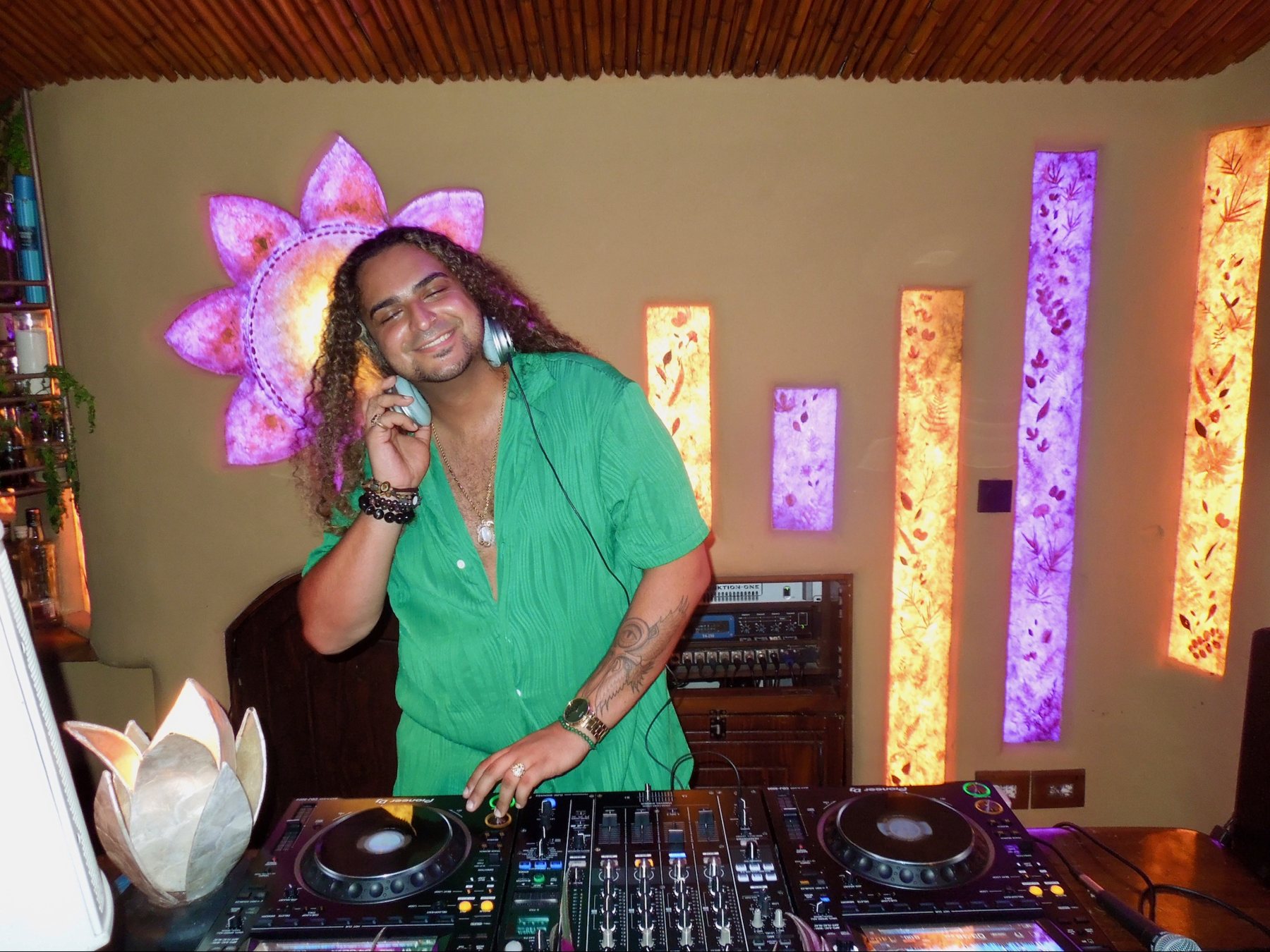 DJ on the decks under coloured light at the jungle party