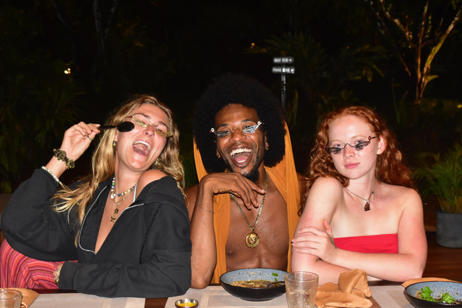 Three friends laughing in funny glasses at the dinner table