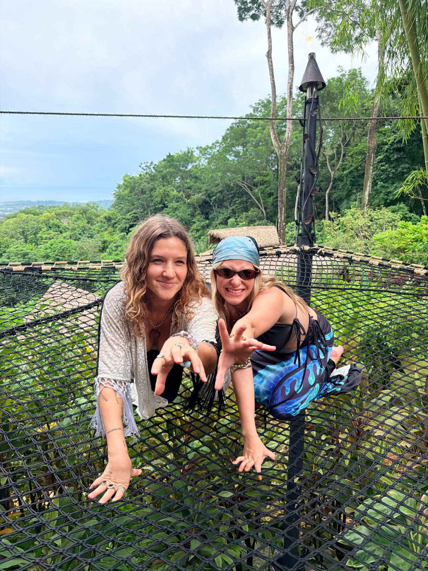 Two friends reaching out playfully from the jungle nets