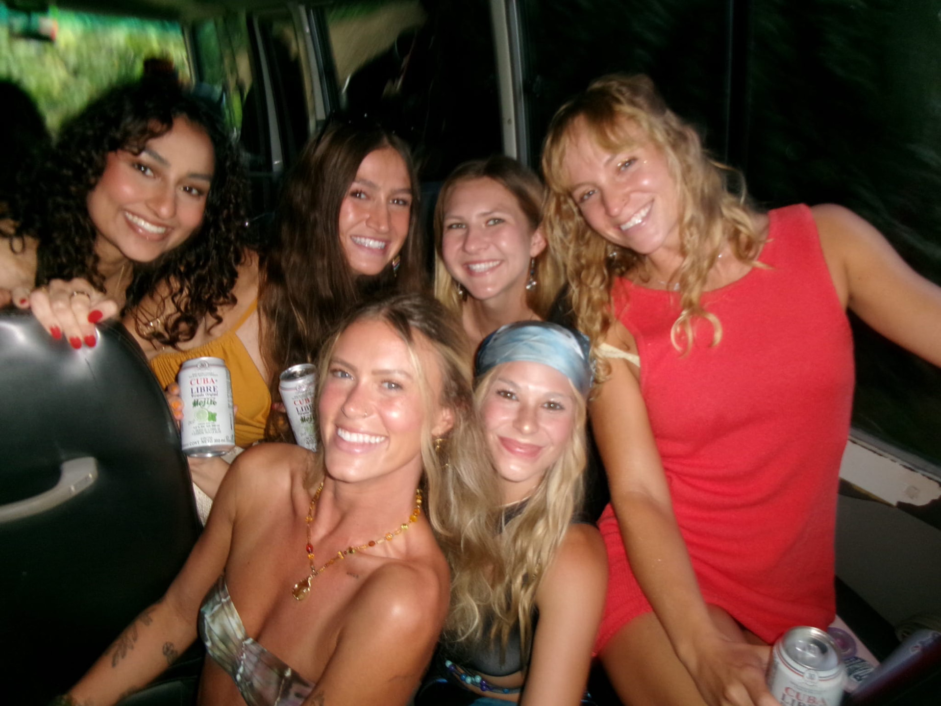 A group of friends smiling together on the party bus at night
