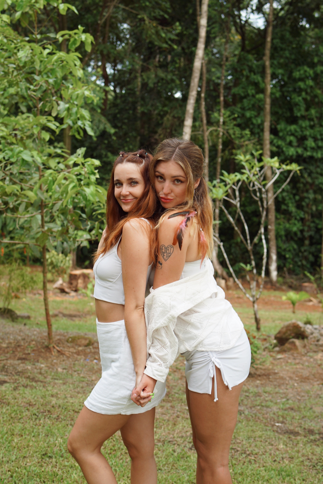 Two friends in white posing back to back in the jungle garden