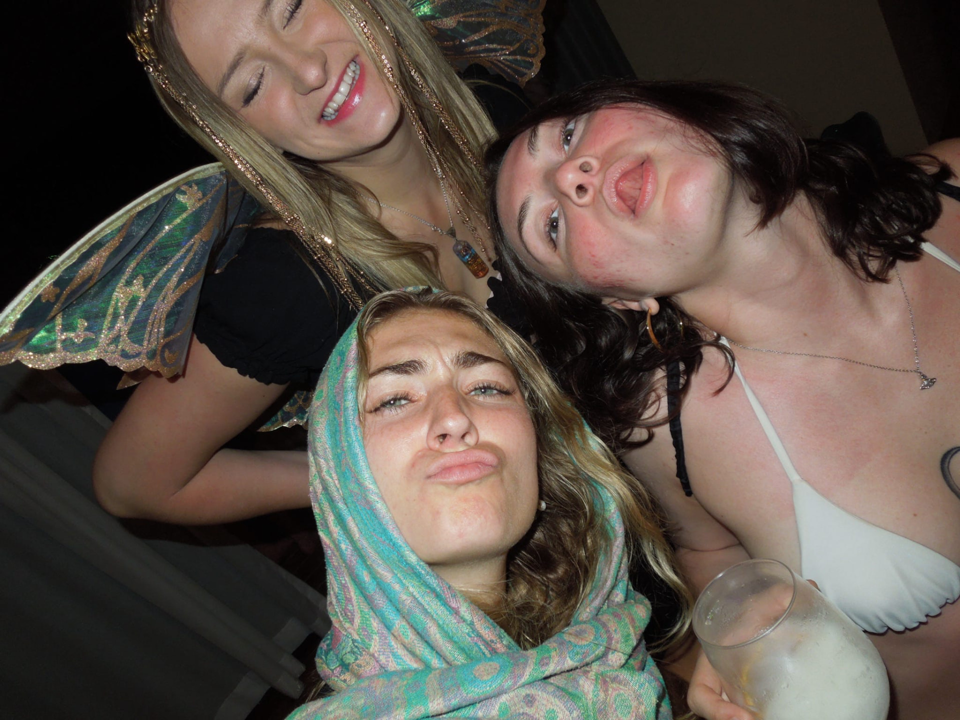 Three friends making silly faces together at the night party