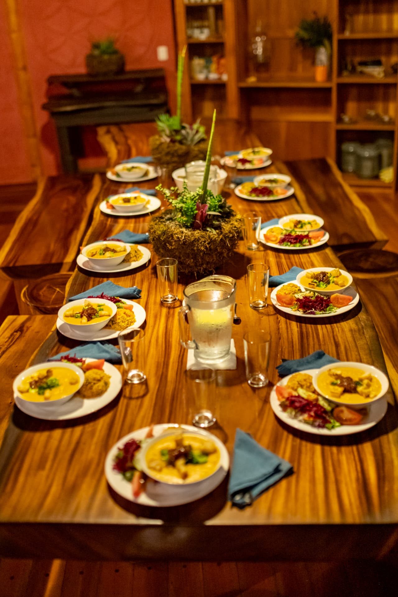 Long wooden table set with curry, salad and fresh bowls