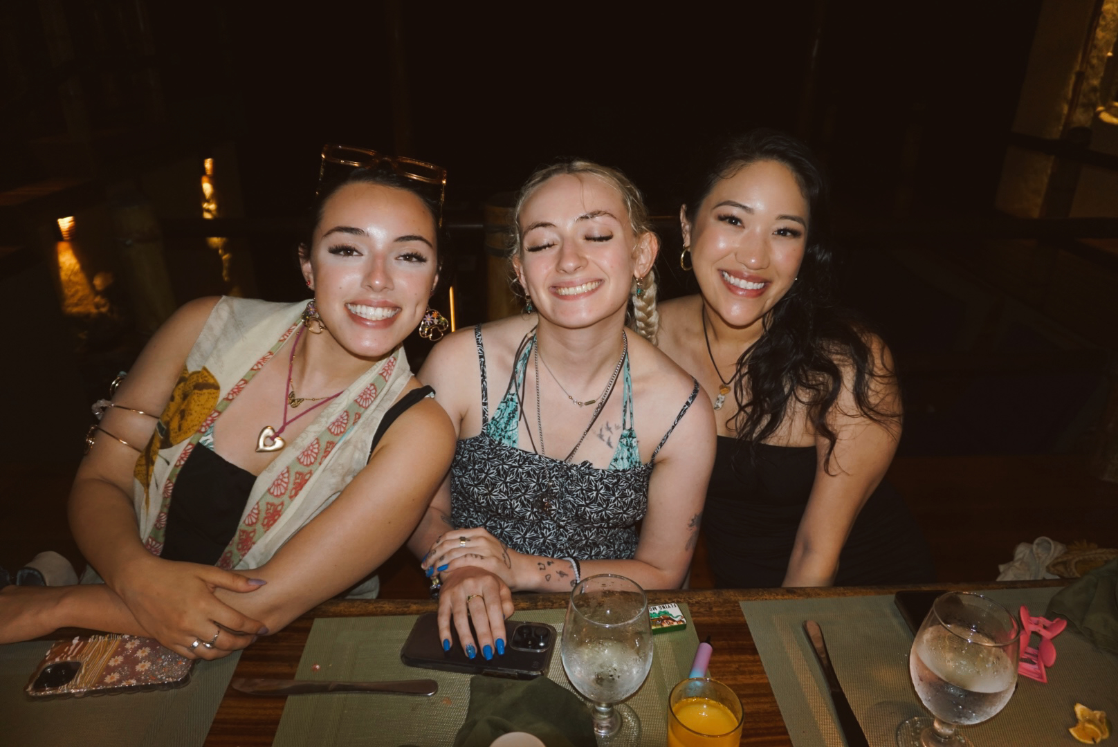 Three friends smiling together over dinner