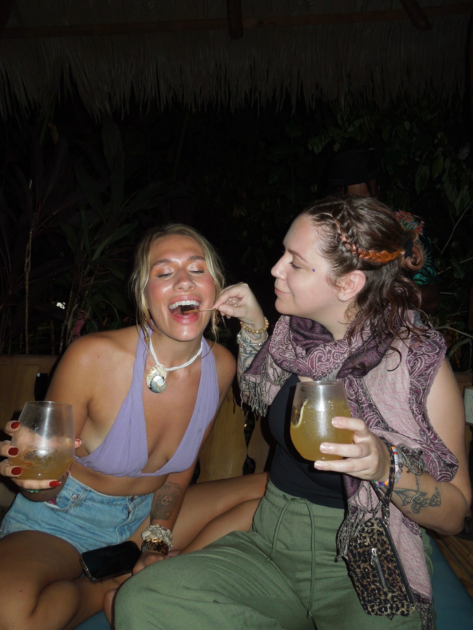 Two friends with drinks in hand in the cabana at night