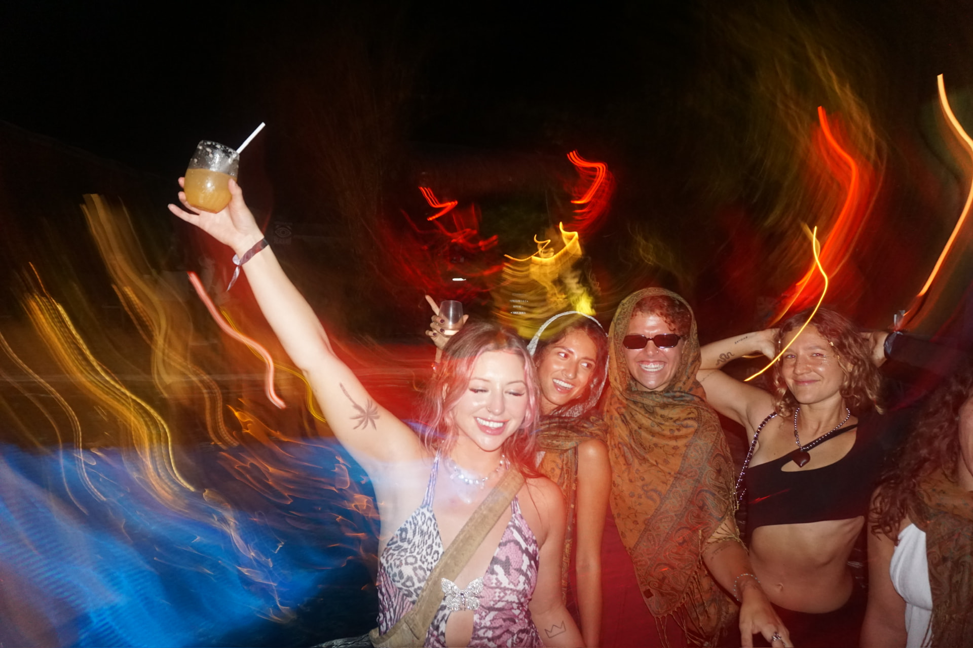 Light-trail chaos on the dance floor, drink held high