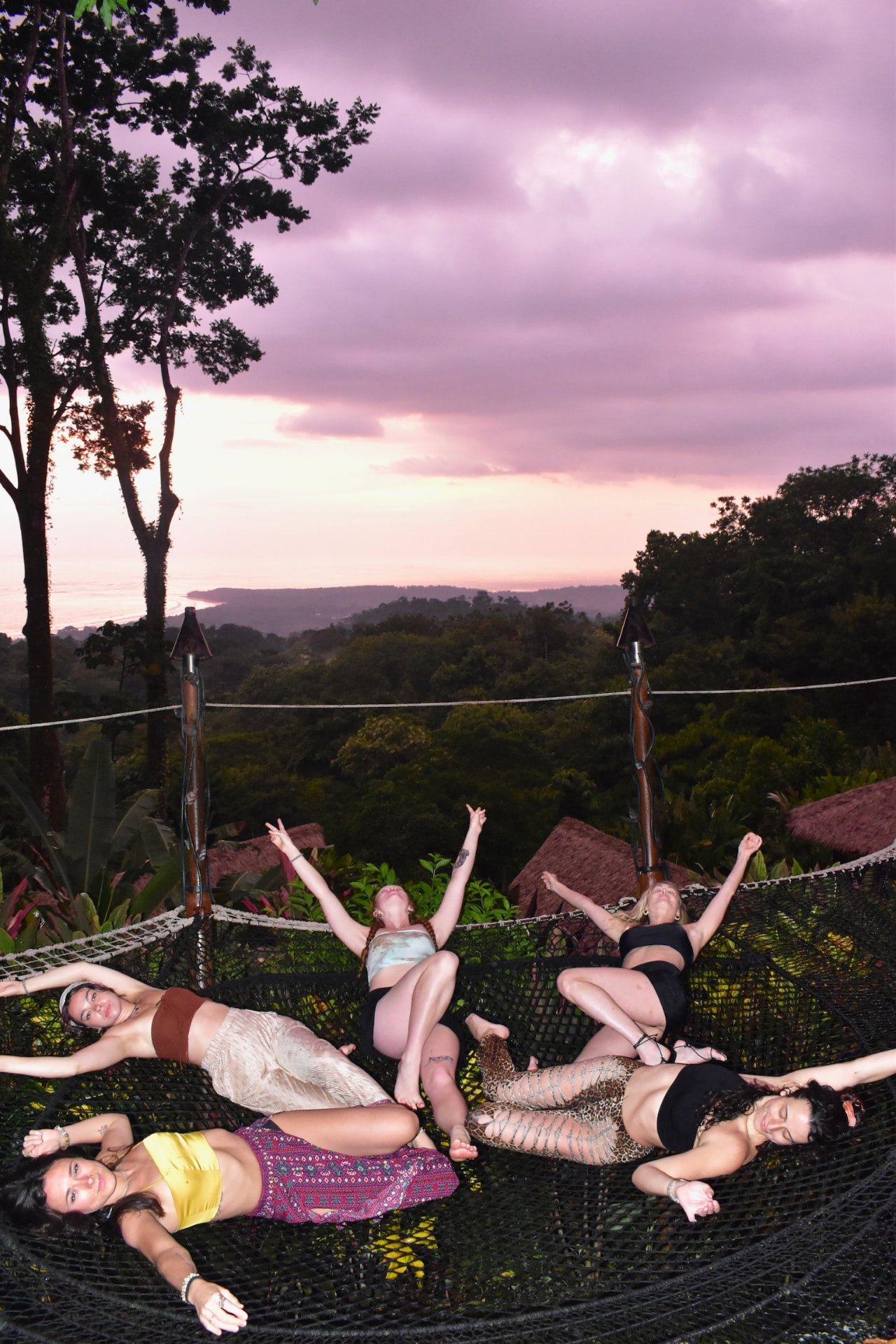 Five friends relaxing in the hammock nets at sunset