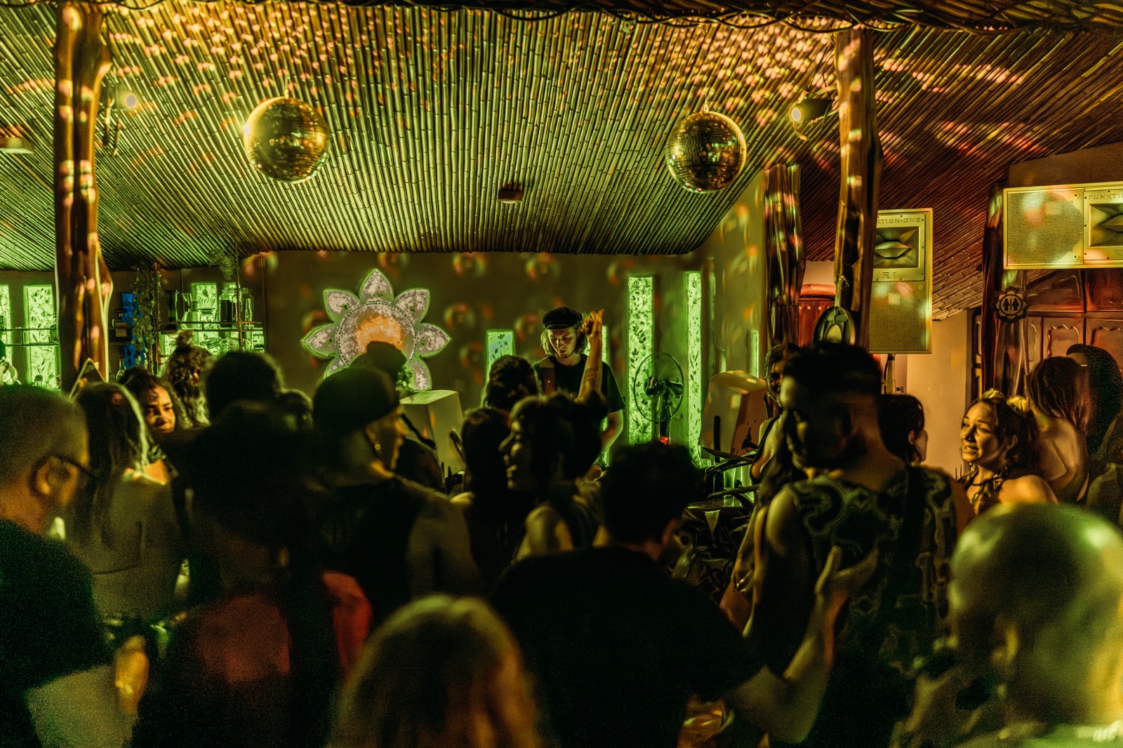 A packed dance floor under disco balls and bamboo ceiling at Selva Armonia