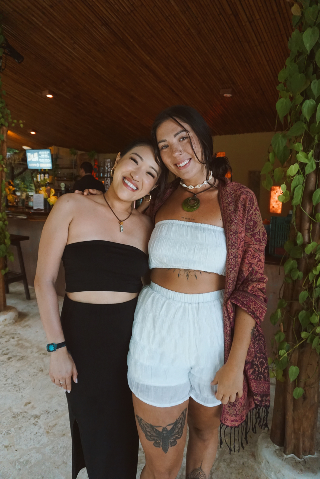 Two friends smiling together at the Selva bar under the bamboo ceiling