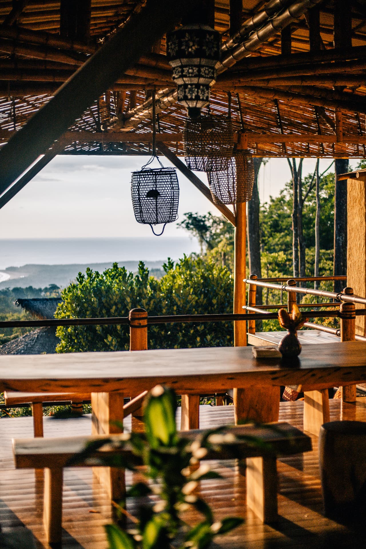 Long wooden dining table under the bamboo palapa with the coastline beyond