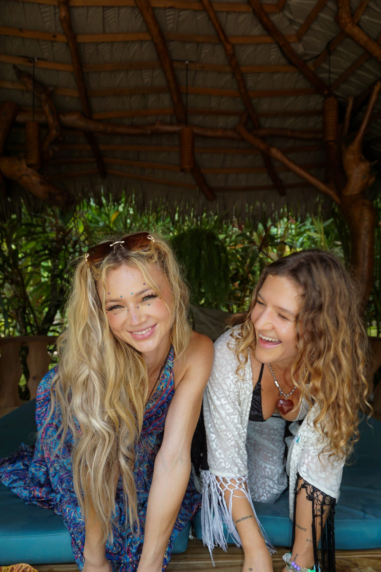 Two friends laughing together on the palapa daybed